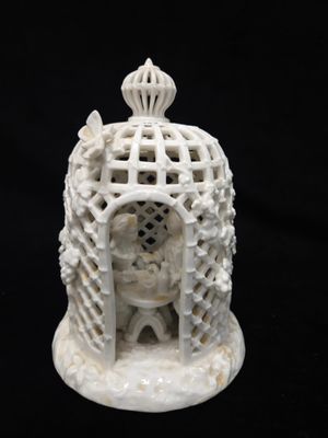 une figurine blanche représentant un oiseau dans une cage, sur fond noir