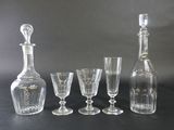 five wine glasses and a decanter on a table