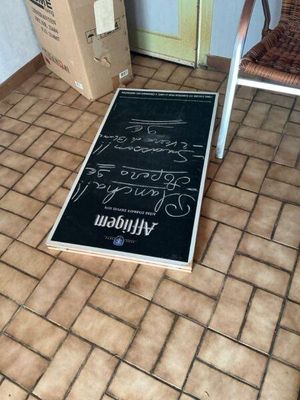 a sign on the floor of a room with a chair next to it