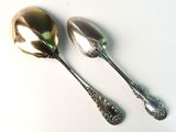 two silver spoons sitting next to each other on a table