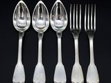 six cuillères et une fourchette sont alignées sur une surface noire