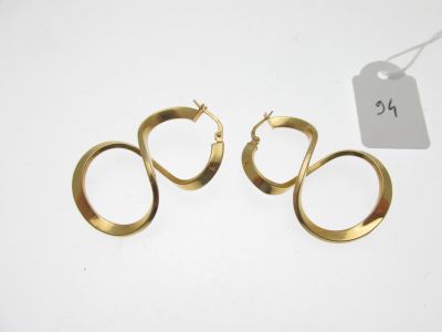 deux paires de boucles d'oreilles en or sur fond blanc