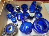 de nombreux objets en verre bleu dans une boîte posée par terre