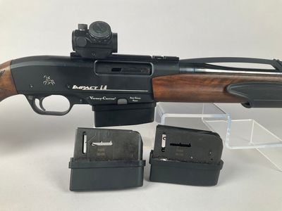 the rifle is sitting next to a magazine holder and two magazines