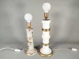 une paire de lampes de table blanches et dorées posées sur une surface grise