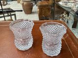 two glass vases sitting on a table in front of a glass case