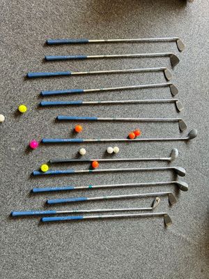 many golf clubs and balls laid out on the floor