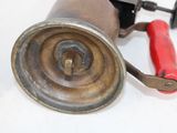 a small metal object with a red handle on a white surface