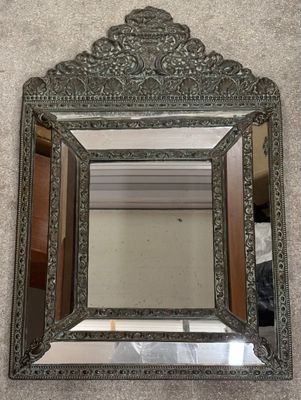 an ornate silver mirror on the wall in a room