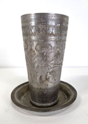 a silver cup sitting on a saucer on a plate