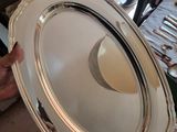 a person holding a silver platter with a white plate on it