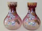 deux vases avec des fleurs peintes dessus, posés sur une table