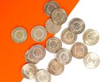 quelques pièces d'argent sont dispersées sur un fond orange et blanc