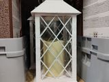 a white lantern with a candle inside of it on a shelf