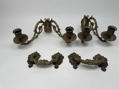 trois bougeoirs en laiton ancien et un porte-bougie posés sur une table
