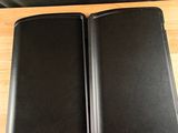 two black speakers on a wooden table with a black chair in the background