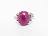 gros plan d'une bague en pierre rose sur une surface blanche
