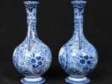 pair of blue and white vases sitting on a black surface