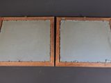 pair of wooden framed mirrors with glass inserts on a wall