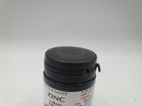 a close up of a jar of black ink on a white surface