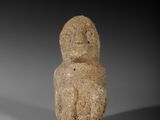 une petite figurine en pierre représentant un homme avec un oiseau sur la tête