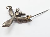 a silver dragonfly brooch on a white surface