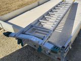 a trailer with a flat bed sitting on top of a gravel field