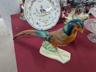 a bird figurine sitting on a table next to a plate