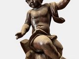 an image of a statue of a child sitting on top of a rock