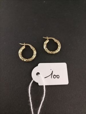 a pair of gold hoop earrings and a tag on a black surface