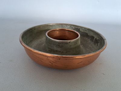 a small metal bowl with a copper rim on a white surface