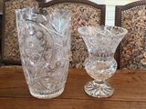 two glass vases sitting on a table in front of a chair