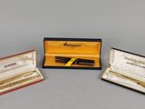 three pens and a pen in a case sitting on a table