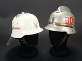pair of firemen ' s helmets on display against a black background