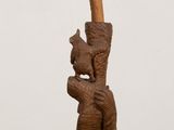 a wooden sculpture of a man holding a stick