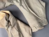 two pairs of tan pants sitting on top of a gray surface