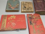 Plusieurs vieux livres sont posés sur une table blanche, à côté d'une paire de ciseaux