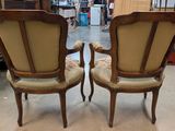 pair of antique chairs with upholstered arms in a store