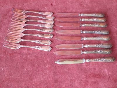 several forks and knives are lined up on a pink cloth
