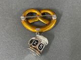 silver and gold pretzel pin with a skull and a pretzel on it