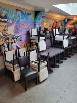 de nombreuses chaises et tables dans un restaurant orné d'une fresque murale