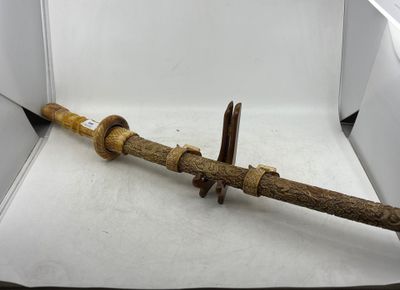 une petite épée en bois dans une boîte posée sur une surface blanche