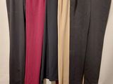 trois paires de pantalons pour femmes suspendues à un portant devant un mur blanc