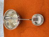 une cuillère en argent et une cuillère en argent posées sur un coussin orange