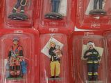 six different firemen figurines in plastic cases
