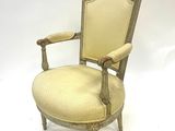 une vieille chaise avec une assise rembourrée beige et un cadre en bois