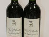 two bottles of red wine sitting on top of a white table