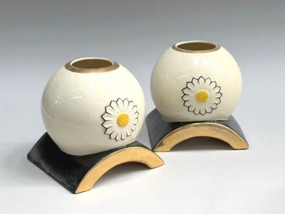 two vases with flowers on them on a stand