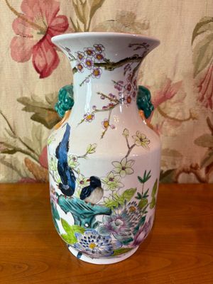 un vase blanc orné d'oiseaux, posé sur une table