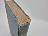 an old book sitting on top of a table on a white surface
